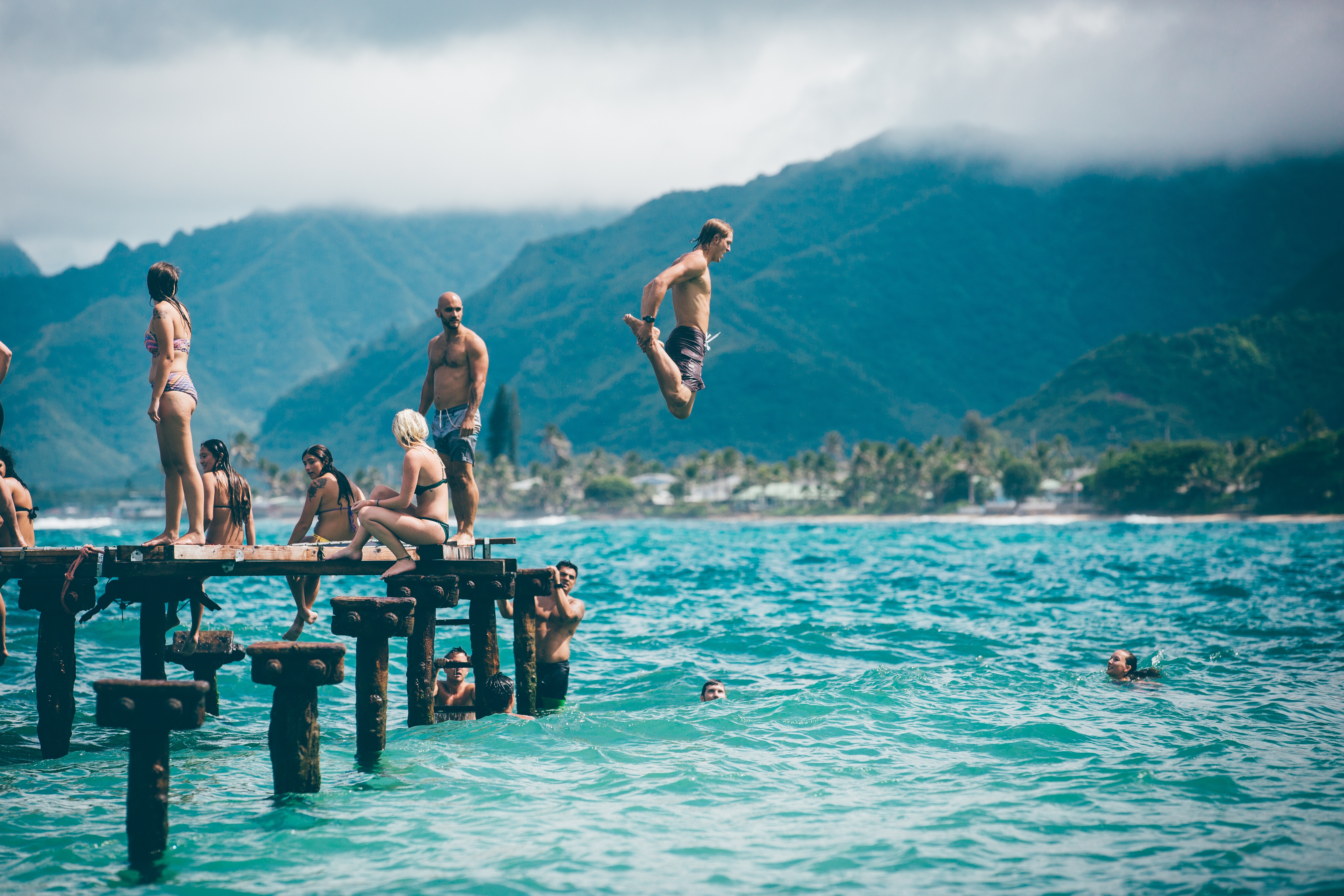 young male jumping from a height into a body of water