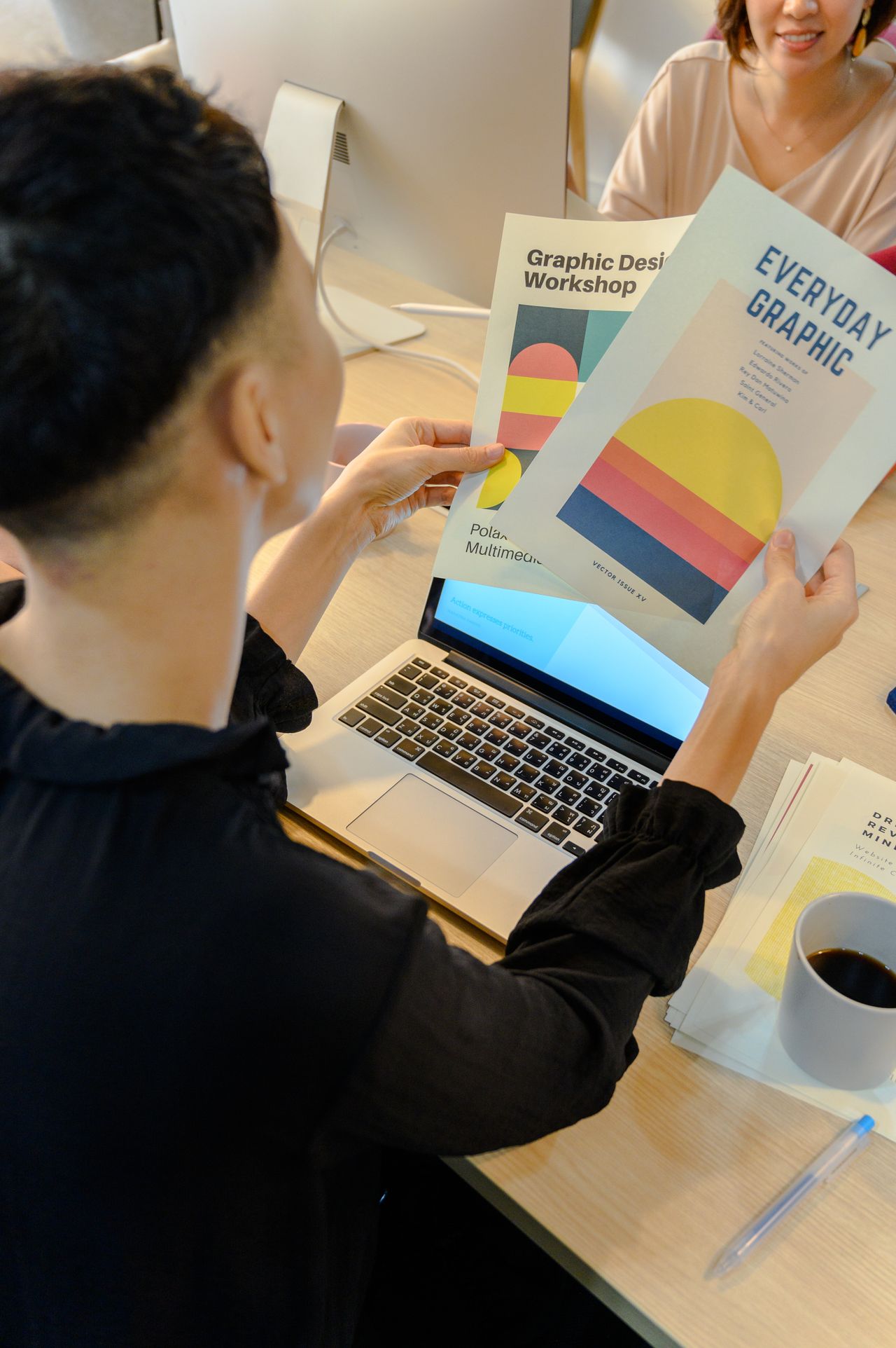 Designer holding printed brochures next to a laptop