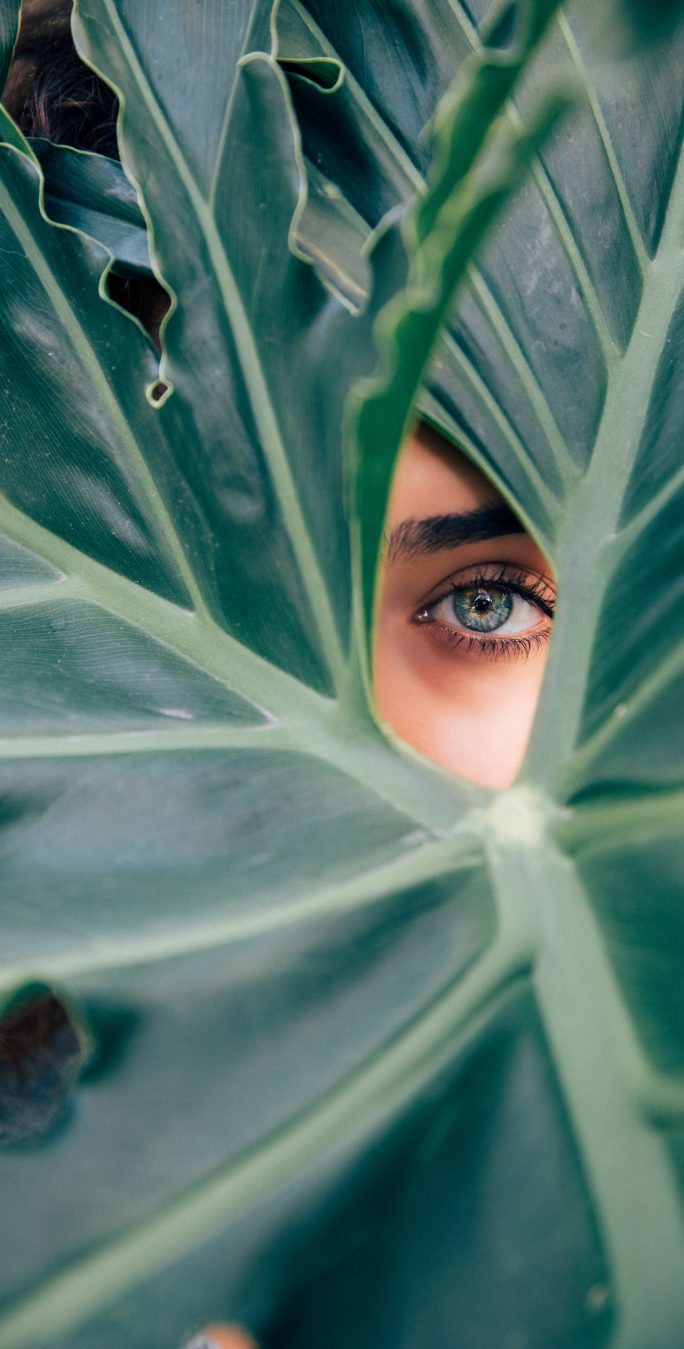 woman peeking through foliage
